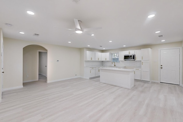 kitchen with decorative backsplash, ceiling fan, sink, light hardwood / wood-style flooring, and white cabinetry