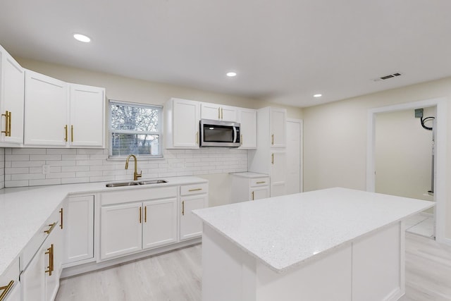 kitchen with white cabinets, decorative backsplash, sink, and a center island