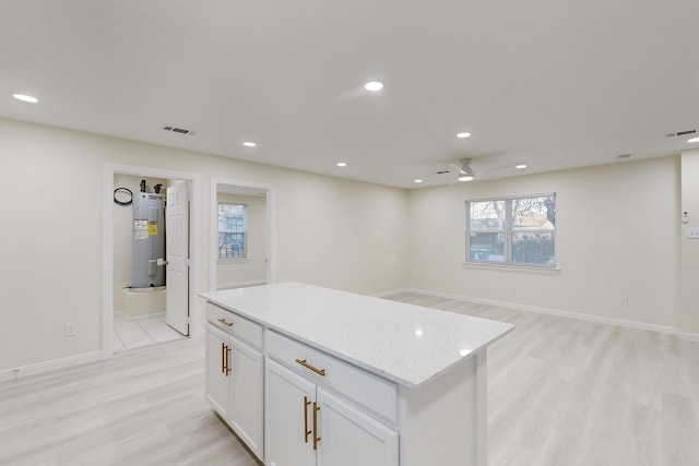 kitchen featuring white cabinets, a center island, light hardwood / wood-style floors, and water heater