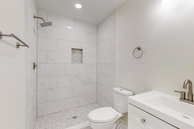 bathroom featuring tiled shower, vanity, and toilet