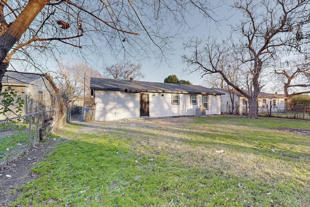 rear view of property featuring a lawn and central AC unit