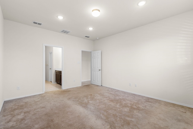 unfurnished bedroom with light colored carpet and connected bathroom