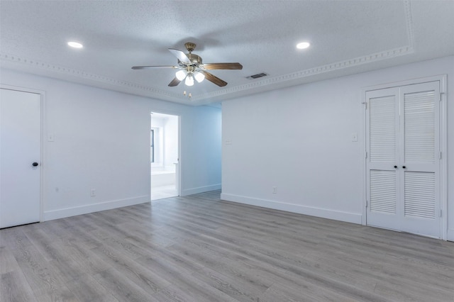 unfurnished room with ceiling fan, light wood-type flooring, and a textured ceiling