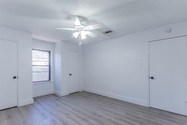 unfurnished bedroom featuring ceiling fan, light wood-type flooring, and a textured ceiling