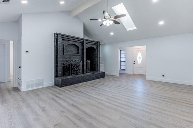 unfurnished living room with a brick fireplace, light hardwood / wood-style floors, beam ceiling, and a skylight