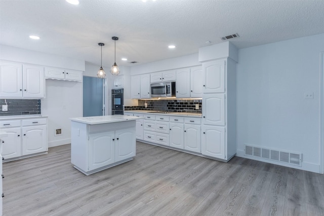 kitchen with pendant lighting, a center island, tasteful backsplash, white cabinetry, and stainless steel appliances