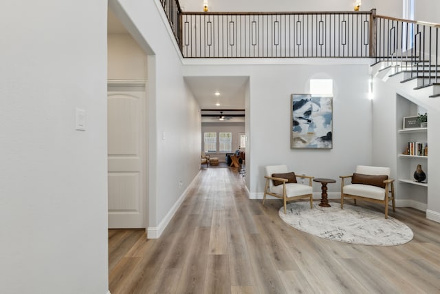 hall with light hardwood / wood-style flooring and a high ceiling