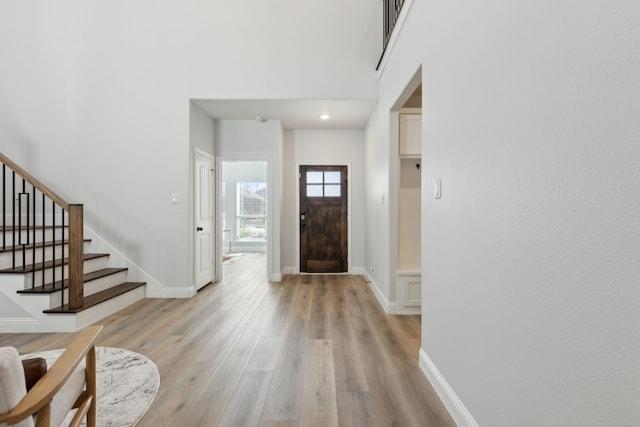 entrance foyer featuring a towering ceiling and light wood-type flooring