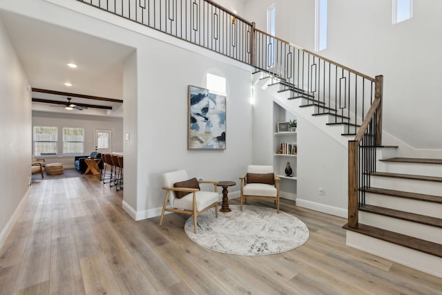 interior space with a high ceiling, ceiling fan, baseboards, and wood finished floors