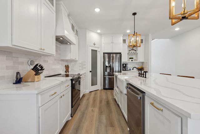 kitchen featuring premium range hood, white cabinets, stainless steel appliances, and pendant lighting