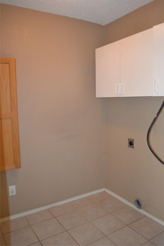 laundry area with light tile patterned floors, cabinets, a textured ceiling, and hookup for an electric dryer