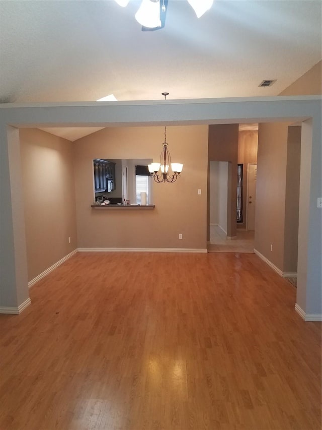 unfurnished room featuring lofted ceiling, wood-type flooring, and a chandelier