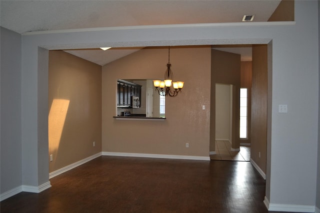 spare room featuring plenty of natural light, dark hardwood / wood-style flooring, lofted ceiling, and a chandelier