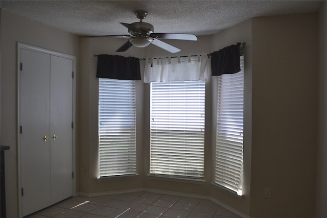 tiled spare room with a textured ceiling and ceiling fan