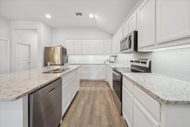 kitchen featuring stainless steel appliances, sink, a center island with sink, white cabinets, and lofted ceiling