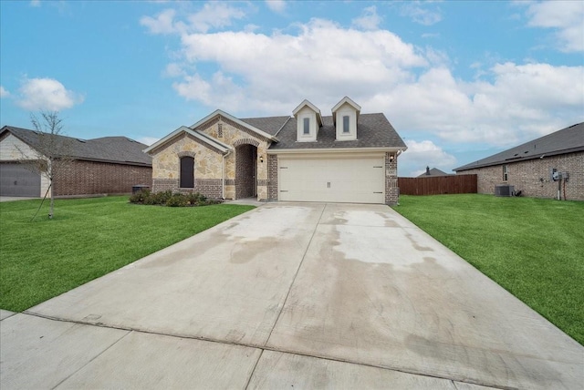 view of front of home featuring a garage, a front yard, and central AC