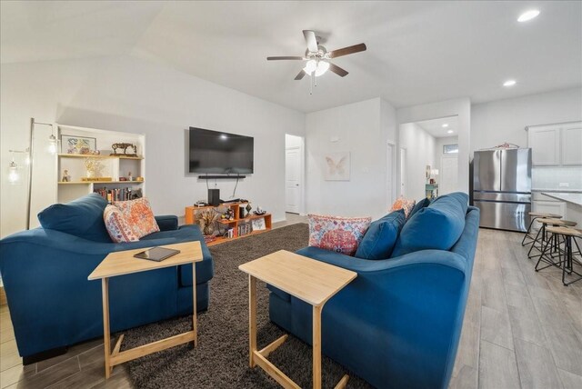 living room featuring ceiling fan, light hardwood / wood-style floors, and lofted ceiling