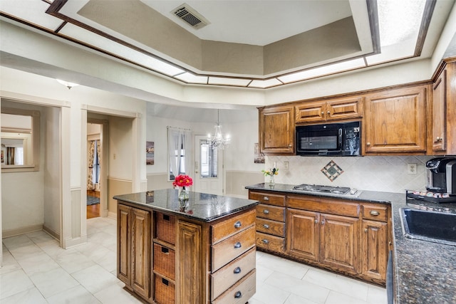 kitchen featuring hanging light fixtures, an inviting chandelier, tasteful backsplash, stainless steel gas stovetop, and a kitchen island