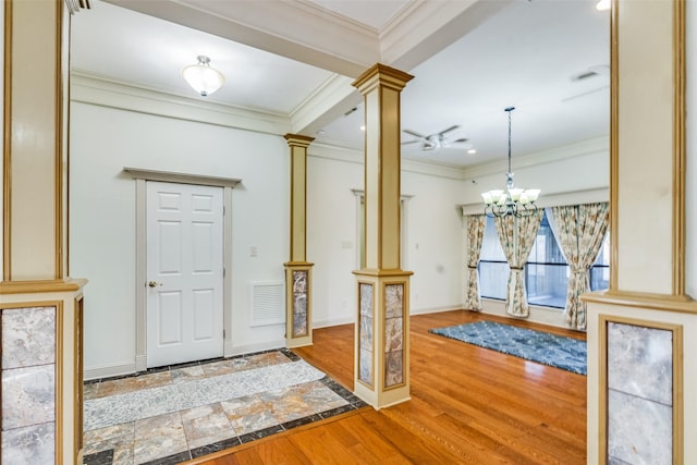 entrance foyer featuring hardwood / wood-style floors, ceiling fan with notable chandelier, decorative columns, and ornamental molding