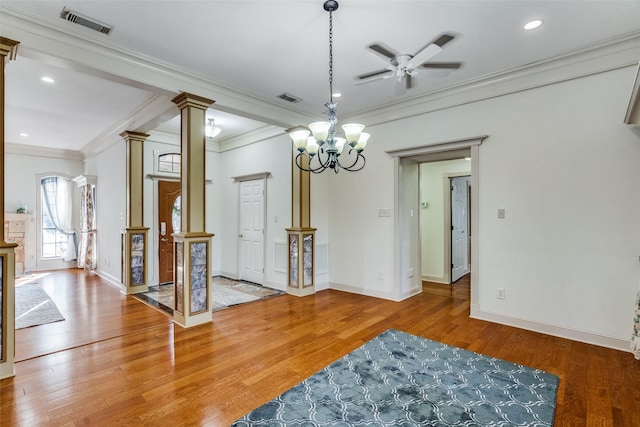 dining area featuring ceiling fan with notable chandelier, hardwood / wood-style flooring, ornate columns, and ornamental molding