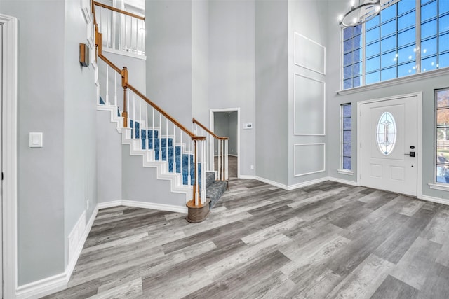 foyer entrance with a chandelier, a towering ceiling, and wood-type flooring