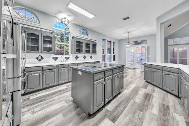 kitchen featuring tasteful backsplash, black electric cooktop, pendant lighting, gray cabinets, and a kitchen island