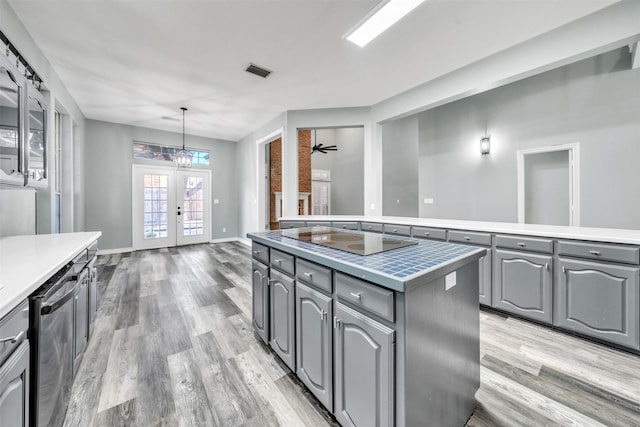 kitchen with stainless steel dishwasher, pendant lighting, gray cabinets, black electric stovetop, and a kitchen island