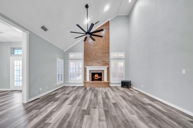 unfurnished living room with a fireplace, hardwood / wood-style flooring, high vaulted ceiling, and crown molding