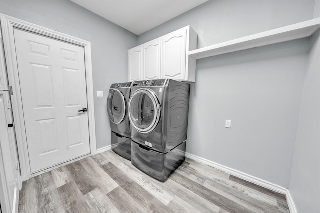 laundry area featuring cabinets, washing machine and dryer, and light hardwood / wood-style floors