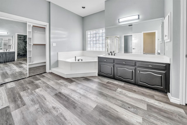 bathroom with wood-type flooring, vanity, and shower with separate bathtub