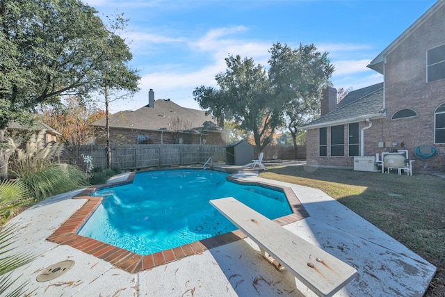 view of pool featuring a yard, a storage unit, and a diving board