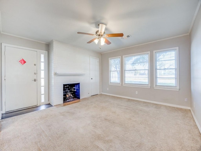 unfurnished living room featuring ceiling fan, crown molding, a fireplace, and light carpet