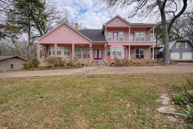 view of property with covered porch, french doors, a balcony, and a front lawn