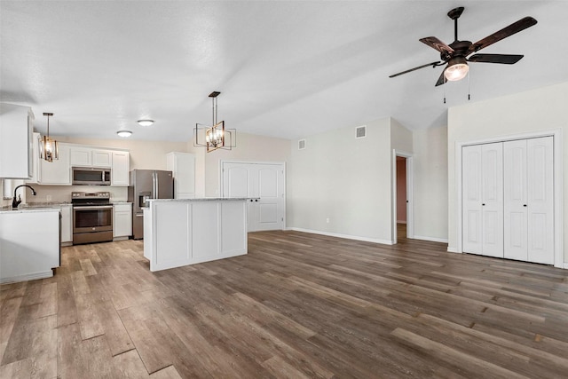 kitchen featuring dark hardwood / wood-style flooring, stainless steel appliances, a kitchen island, pendant lighting, and white cabinetry