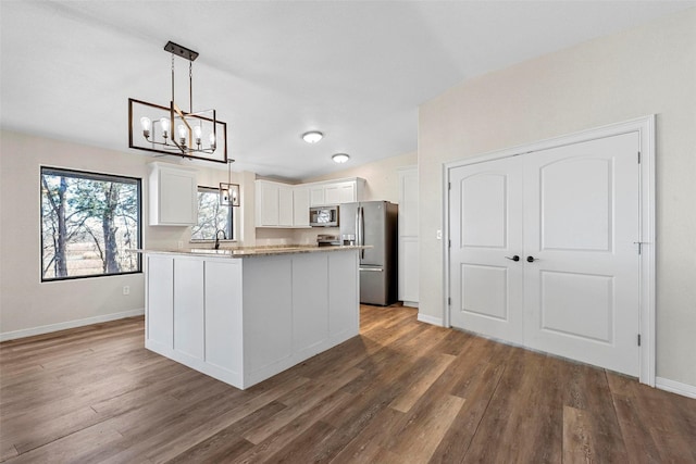 kitchen with appliances with stainless steel finishes, decorative light fixtures, a kitchen island, and white cabinets