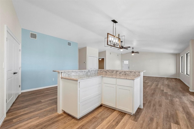 kitchen featuring a kitchen island, white cabinets, hanging light fixtures, light stone counters, and light wood-type flooring