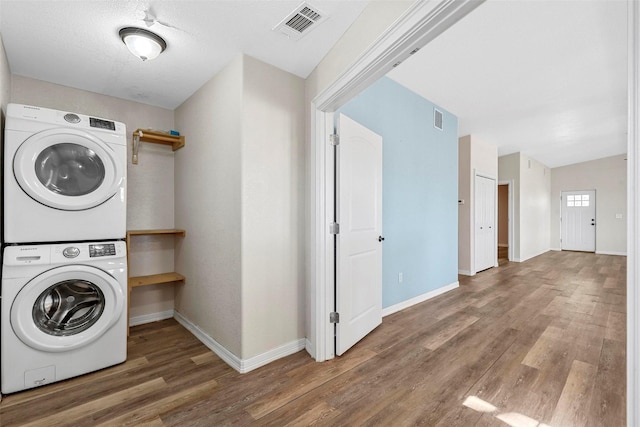 laundry area featuring hardwood / wood-style floors and stacked washer and clothes dryer