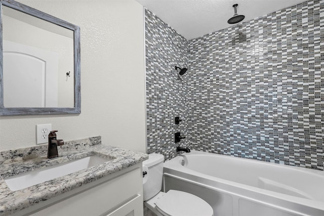 full bathroom featuring vanity, a textured ceiling, toilet, and tiled shower / bath