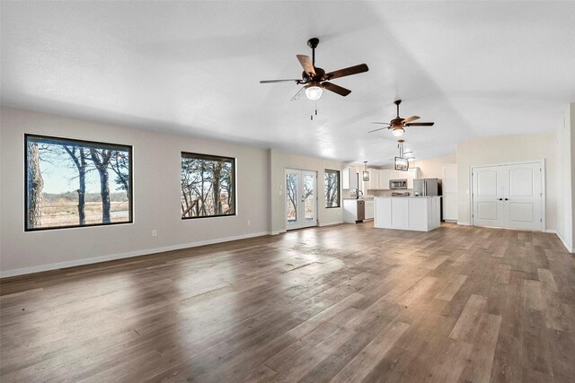 unfurnished living room with ceiling fan, vaulted ceiling, and hardwood / wood-style flooring