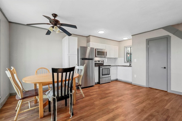 kitchen with sink, stainless steel appliances, tasteful backsplash, light hardwood / wood-style flooring, and white cabinets