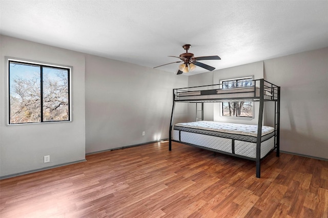 unfurnished bedroom with multiple windows, hardwood / wood-style flooring, and a textured ceiling