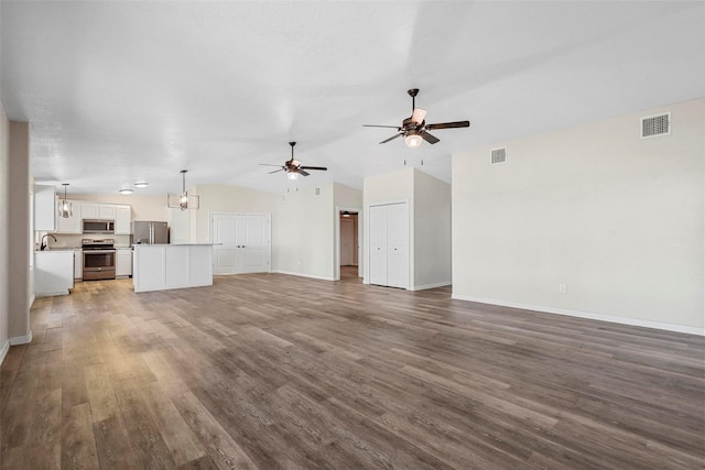 unfurnished living room featuring lofted ceiling, hardwood / wood-style floors, ceiling fan with notable chandelier, and sink