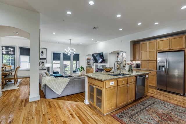 kitchen featuring a kitchen island with sink, sink, light hardwood / wood-style flooring, light stone counters, and stainless steel appliances