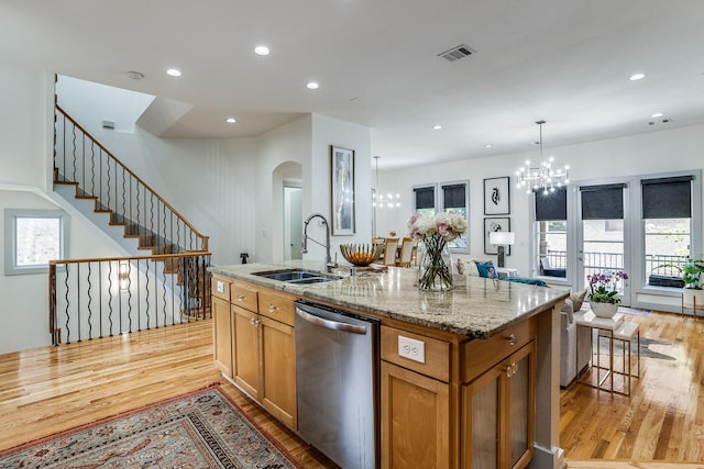 kitchen with sink, stainless steel dishwasher, an island with sink, light hardwood / wood-style floors, and decorative light fixtures