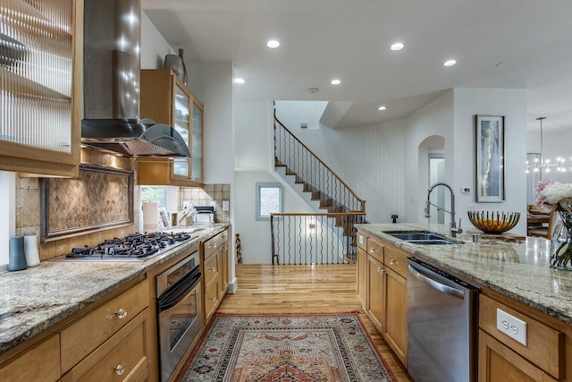 kitchen with sink, decorative backsplash, light hardwood / wood-style floors, stainless steel appliances, and extractor fan