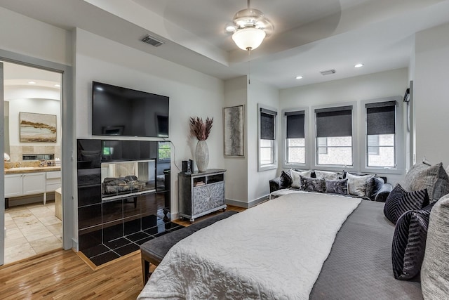 bedroom with hardwood / wood-style floors, connected bathroom, and ceiling fan