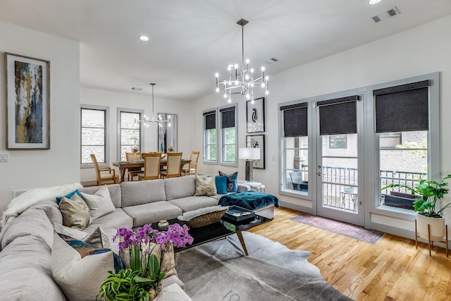 living room with light hardwood / wood-style floors and an inviting chandelier