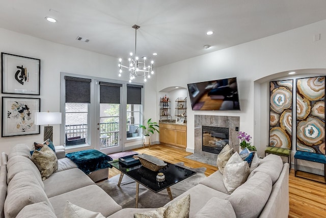 living room featuring hardwood / wood-style floors, a high end fireplace, and an inviting chandelier