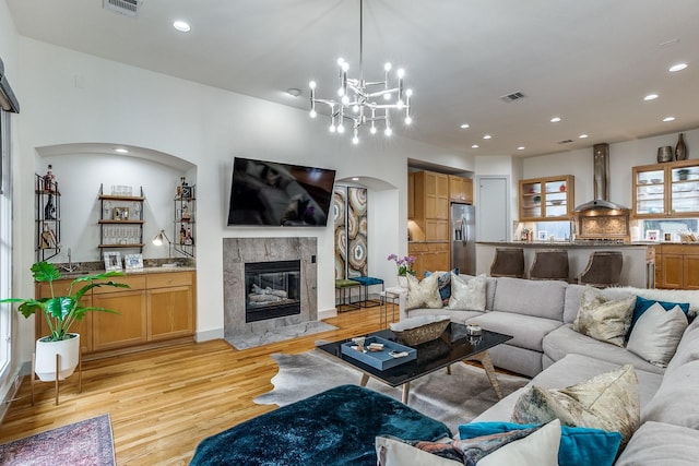 living room with a fireplace, light hardwood / wood-style floors, and an inviting chandelier