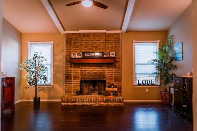 living room with a brick fireplace, a wealth of natural light, dark wood-type flooring, and ceiling fan